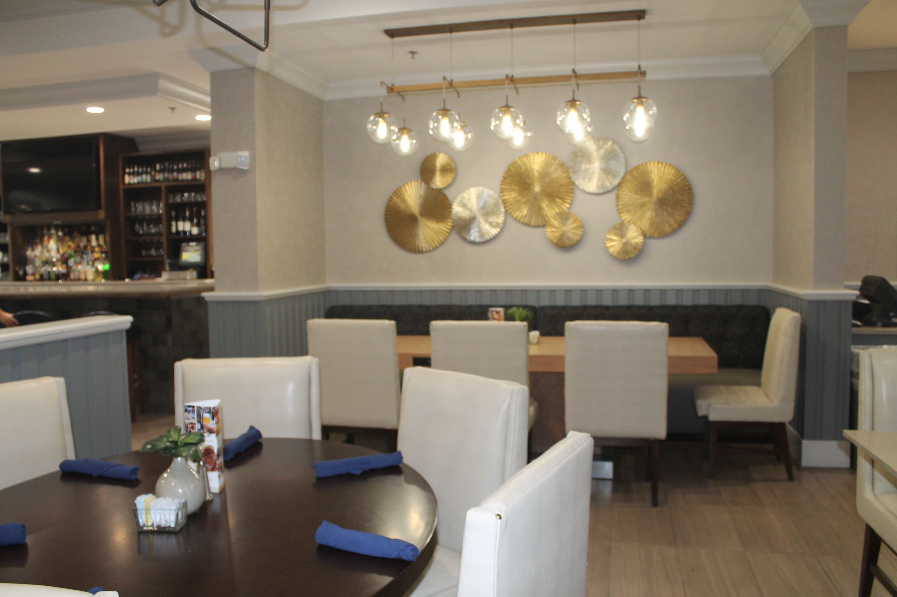 A restaurant with a bar area, round tables, and booths.