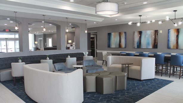 Eine moderne Lobby mit Sitzbereichen, einer Rezeption und Kunstwerken an den Wänden.