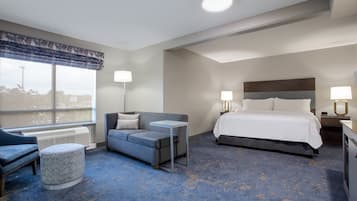Une chambre d’hôtel avec un lit, un canapé, une petite table et une fenêtre donnant sur un paysage agréable.