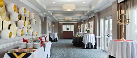 A hotel dining area with tables set for service, a chandelier, and a wall with decorative eggs.