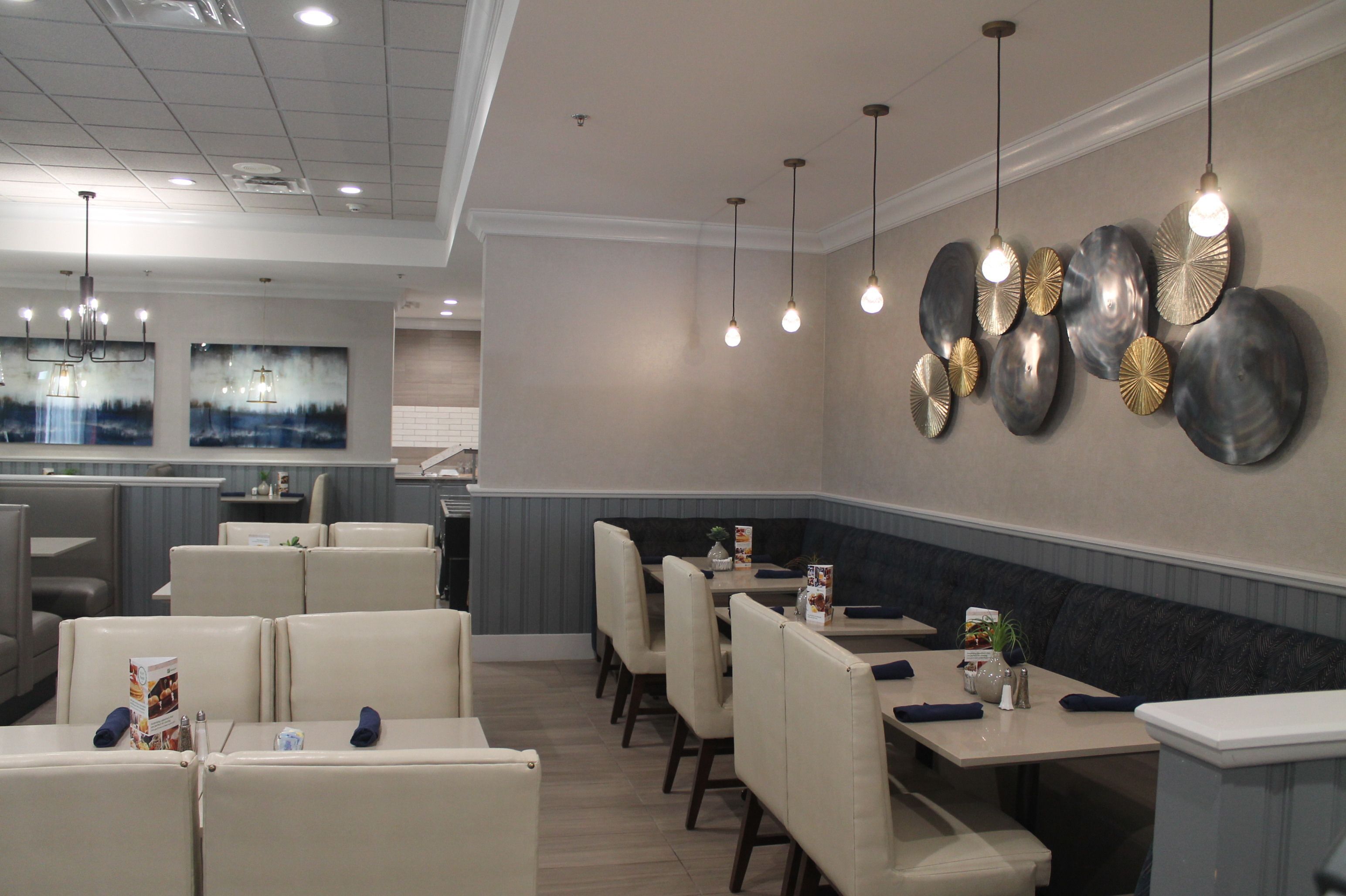 A restaurant with booth seating, pendant lighting, and wall art.