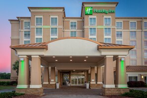 Entree van een Holiday Inn hotel met een modern design, met een grote glazen deur en een overdekt inkomgedeelte.