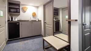 Eine kompakte Küche mit Mikrowelle, Kaffeemaschine und kleinem Kühlschrank.