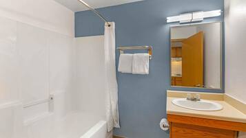 A bathroom with a bathtub, a sink, a mirror, and a towel rack.