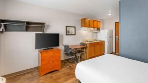 A compact hotel room with a bed, a desk with a chair, a television, a kitchenette, and a wardrobe. - Extended Stay America Select Suites - Las Cruces (Las Cruces)