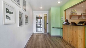 A hallway with framed flags, a reception desk, and a wooden counter. - Extended Stay America Select Suites - Laredo (Laredo)