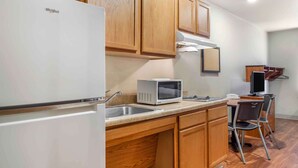 A compact kitchen with wooden cabinets, a built-in microwave, and a refrigerator. - Extended Stay America Select Suites - Laredo (Laredo)