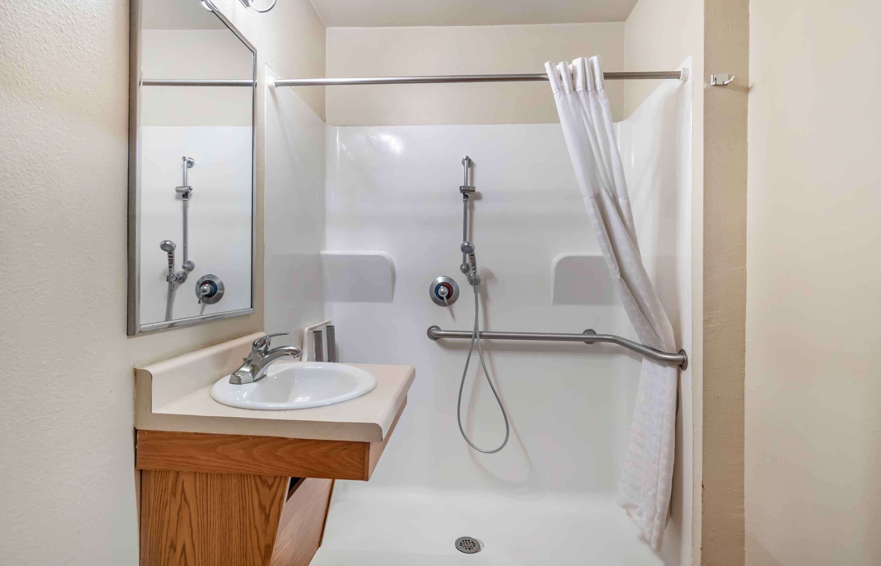 Une salle de bain équipée d’un lavabo, d’un miroir, d’une douche et d’un porte-serviettes.