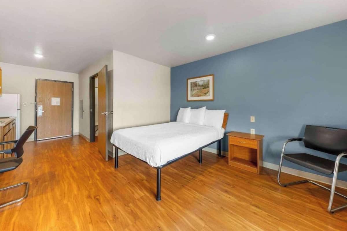 Une chambre à coucher avec un lit, une chaise, une table de chevet et une porte.