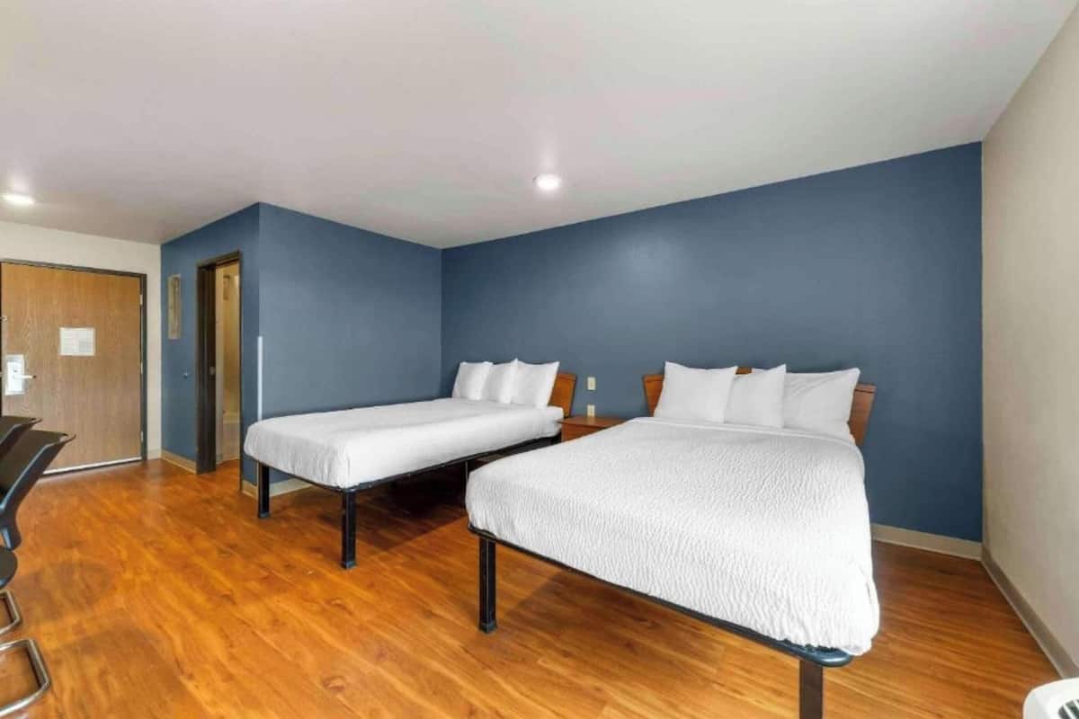 Une chambre avec deux lits, un plancher en bois et une porte.