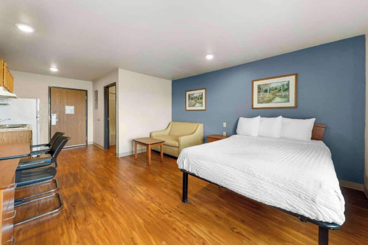 Une chambre d’hôtel avec un lit, un bureau, une chaise et une petite table.