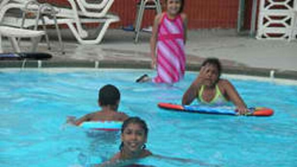 Une piscine où se baignent des enfants et des adultes.