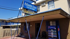 Un motel avec une enseigne bleue sur laquelle on peut lire « Atlantic Inn » et un distributeur automatique de Pepsi.