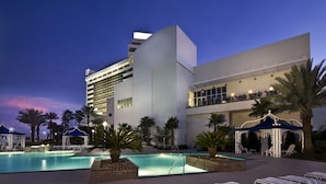 Un hôtel moderne doté d’une grande piscine, d’un espace extérieur aménagé et d’un pavillon couvert.