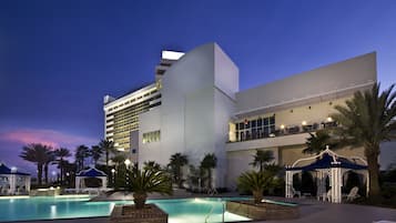 Relax by the rectangular pool surrounded by lounge chairs and umbrellas.