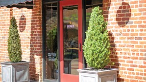 A brick building with a red door and a black awning. There are two potted plants on either side of the door. - Craddock Terry Hotel, Lynchburg, a Tribute Portfolio Hotel (Lynchburg)
