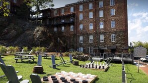 A courtyard with picnic tables, a chessboard, and a building with multiple windows and a balcony. - Craddock Terry Hotel, Lynchburg, a Tribute Portfolio Hotel (Lynchburg)