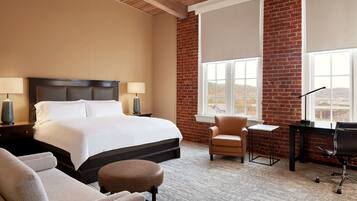 A hotel room with a large bed, a desk, a chair, and a view of the outside.