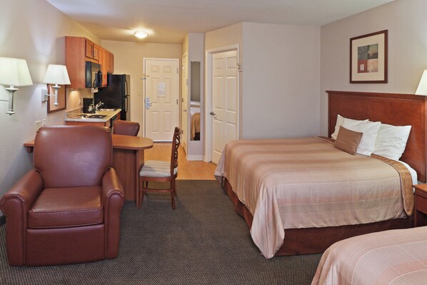 A hotel room with a bed, a desk, a chair, a television, and a painting on the wall.