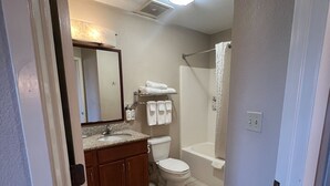 Baño con inodoro, lavamanos, espejo y ducha.