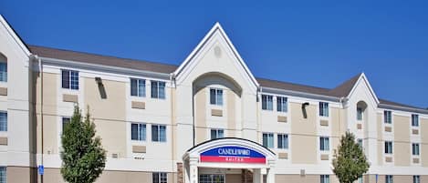 A multi-story hotel with a prominent entrance, a sign indicating it is a Candlewood Suites, and a parking sign.