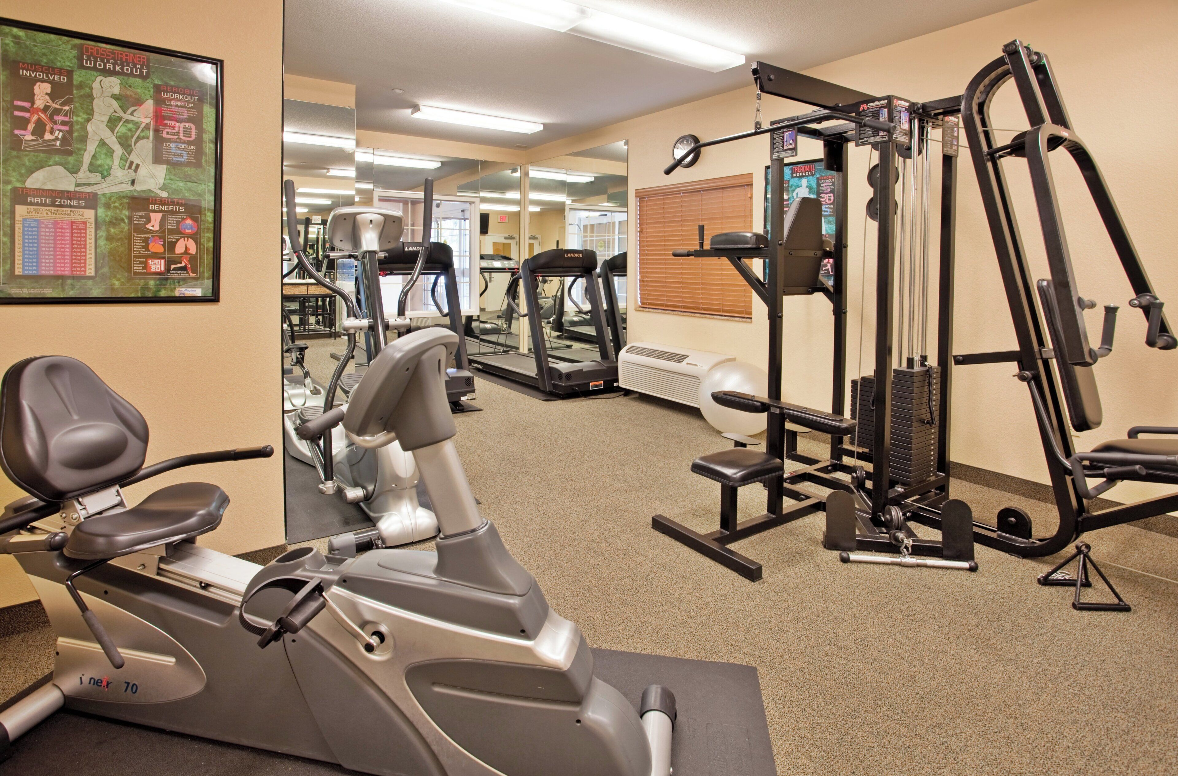 A gym with various exercise equipment including a treadmill, elliptical trainer, and weight machines.