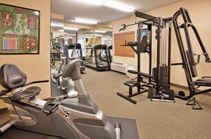 A gym with various exercise equipment including a treadmill, elliptical trainer, and weight machines.