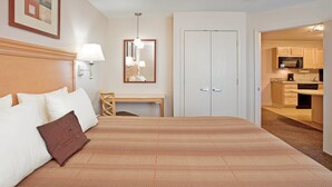 Ein Hotelzimmer mit einem großen Bett, einem Schreibtisch, einem Spiegel und einer Küchenzeile.