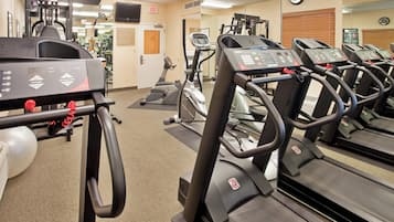 A gym with multiple treadmills, exercise bikes, and a weight machine.