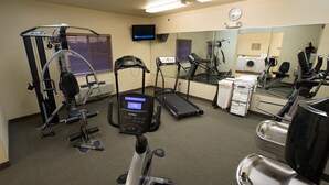 A gym with cardio machines, weight training equipment, and a mirror.