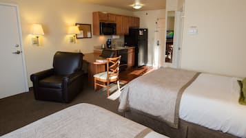 Habitación de hotel con dos camas, un escritorio, una silla, un microondas y un refrigerador.