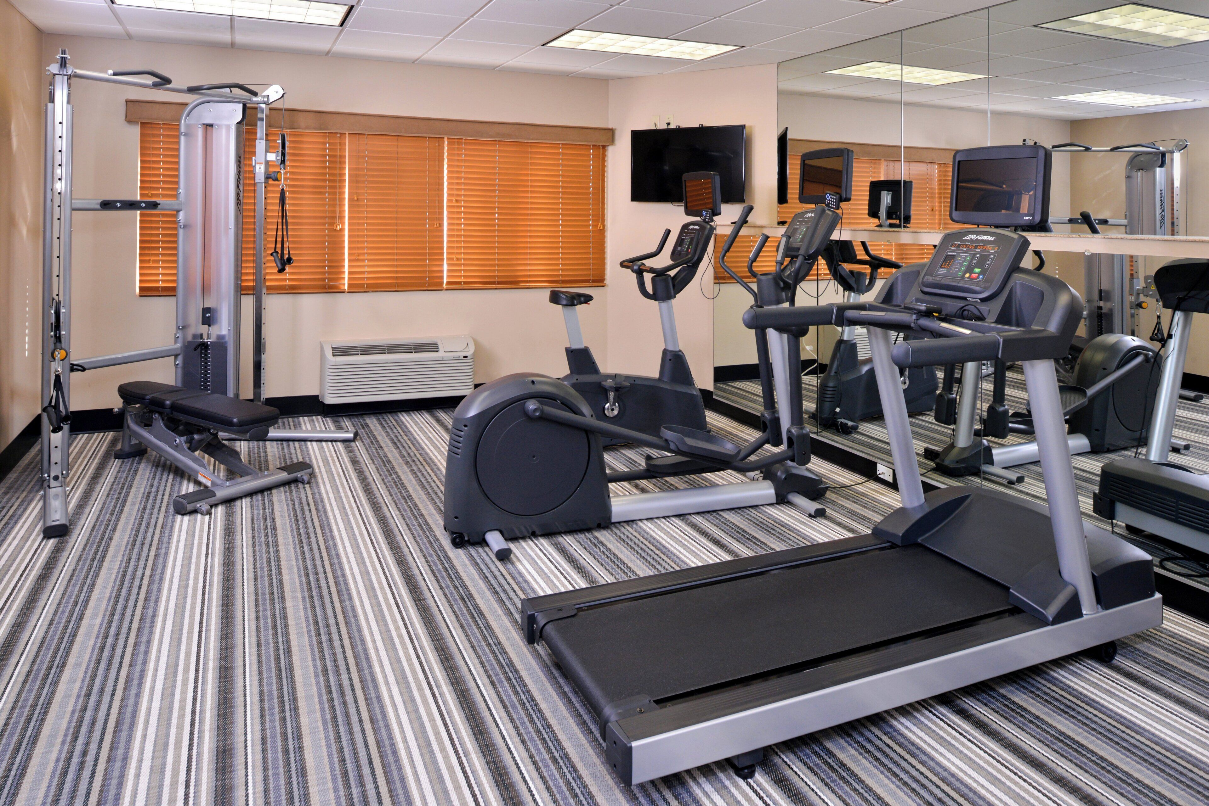 Un gimnasio con equipos de ejercicio variados, incluyendo cintas de correr, bicicletas estáticas y máquinas de pesas.