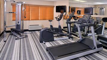 Un gimnasio con equipos de ejercicio variados, incluyendo cintas de correr, bicicletas estáticas y máquinas de pesas.