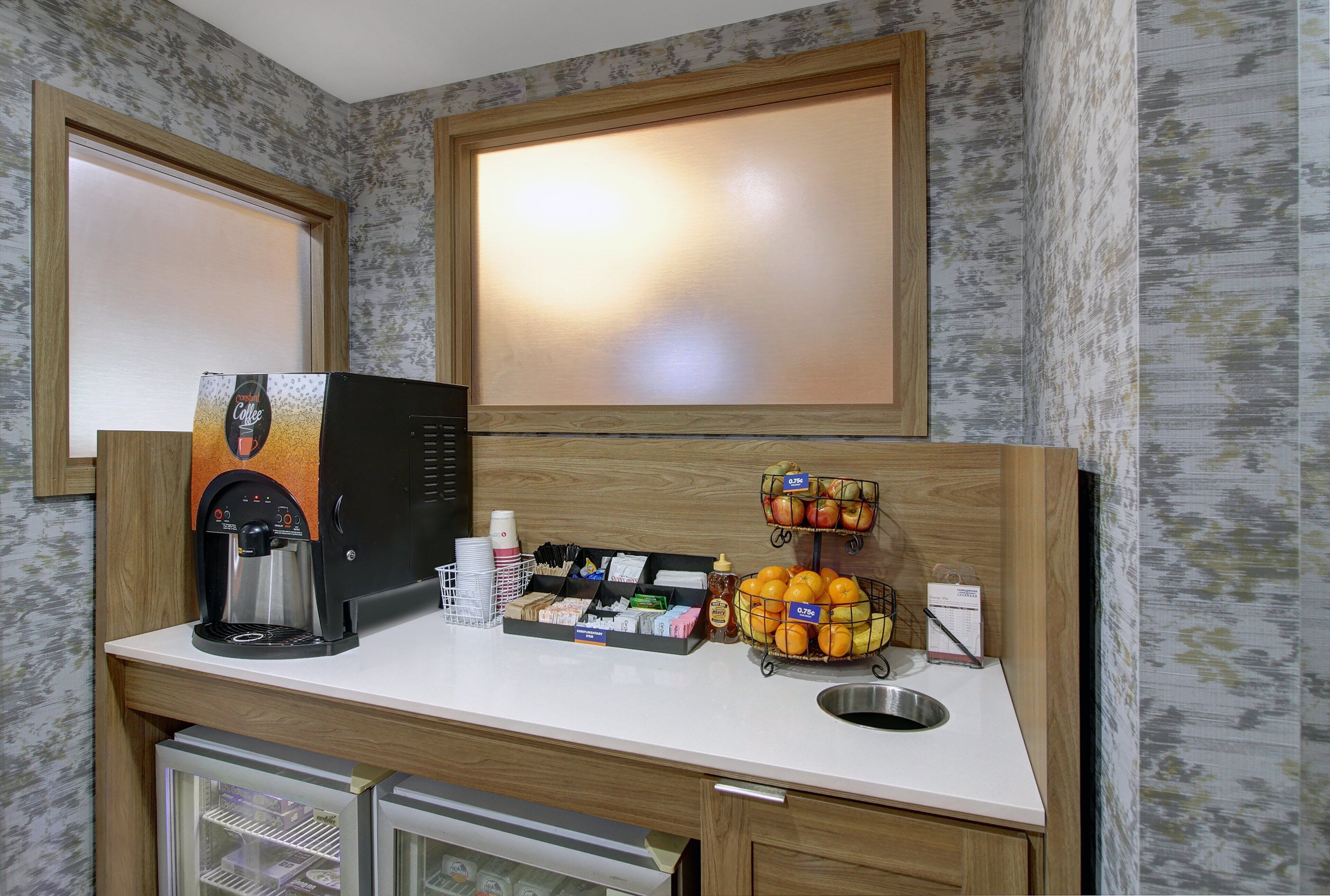 A kitchenette with a coffee machine, a fruit basket, and a mini-fridge.