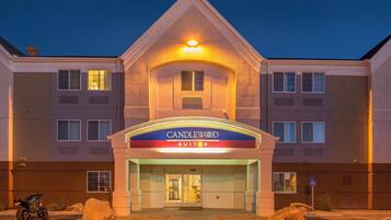 Un hotel con un cartello ben visibile di 'Candlewood Suites', un ingresso chiuso da cancello e un'area di parcheggio con una motocicletta.