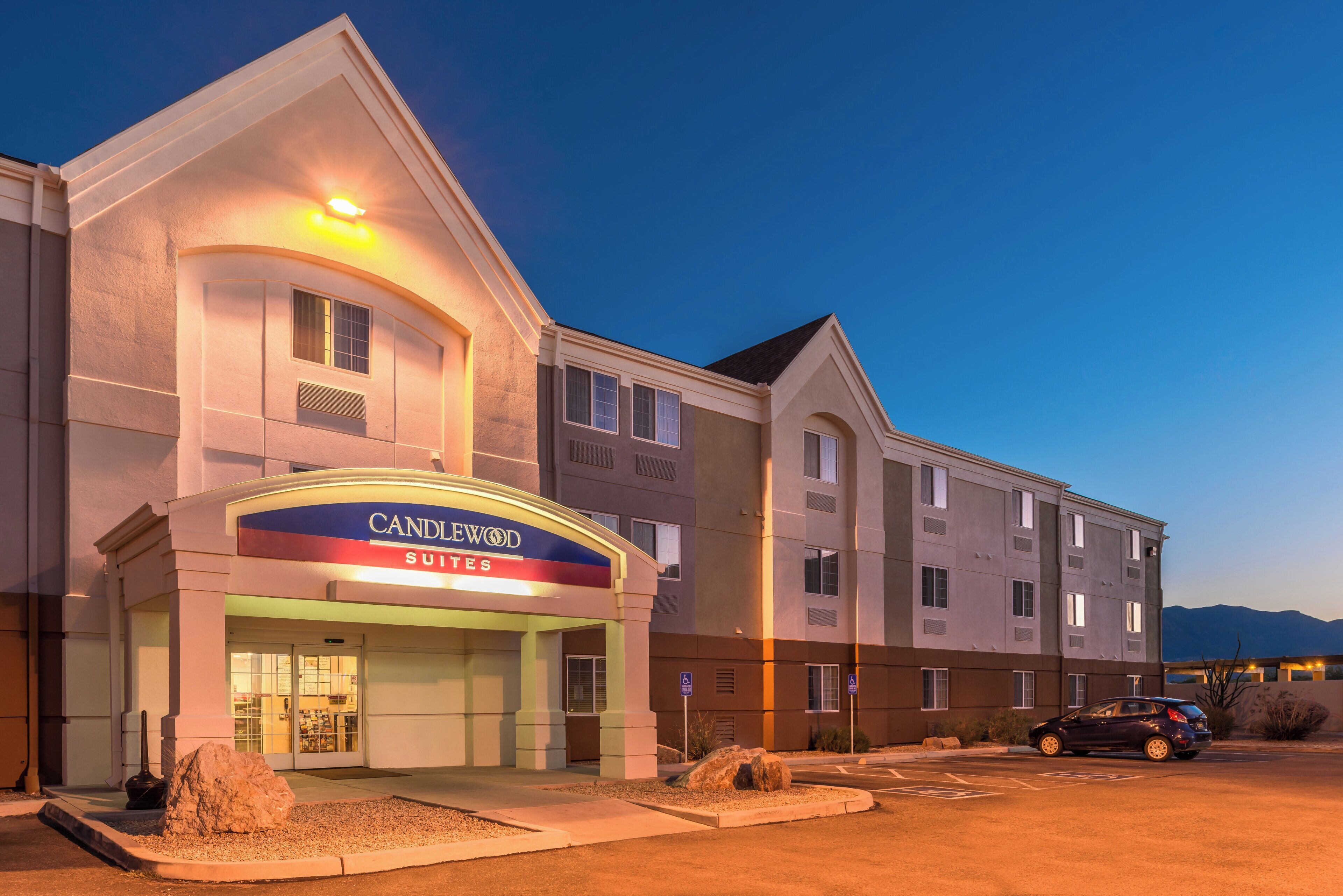 A hotel with a prominent entrance, multiple windows, and a parking lot.