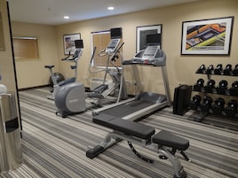 A gym with treadmills, an elliptical, a bench, and a rack of dumbbells.