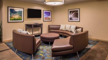 A modern living room with a brown leather sofa, a coffee table, and a flat-screen TV mounted on the wall.