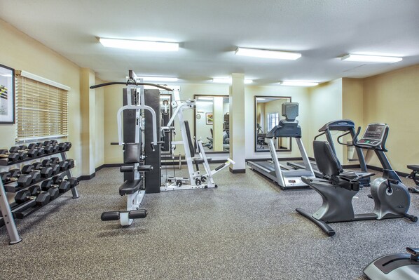 A gym with various exercise equipment including treadmills, elliptical machines, and free weights.