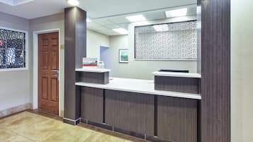 A reception desk with a wooden door and a framed welcome sign.