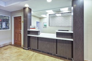 A reception desk with a wooden door and a framed welcome sign. - Candlewood Suites Indianapolis Airport by IHG (Indianapolis)