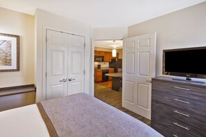 Ein Hotelzimmer mit Bett, Schminktisch, Fernseher und Blick in den Küchenbereich.