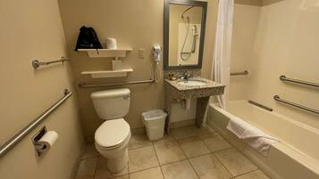 A bathroom with a toilet, sink, and bathtub, equipped with grab bars and a shower.