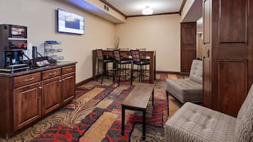 A hotel room with a coffee station, a dining area with chairs and a table, and a patterned carpet.