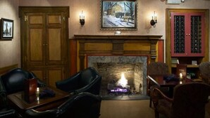 Una habitación acogedora con chimenea, sillones de cuero, una mesa de comedor y un cuadro en la pared.