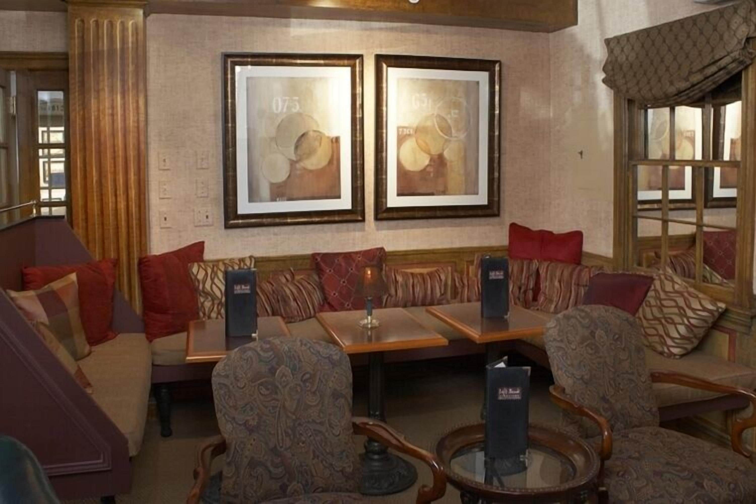 A hotel lobby with a seating area featuring sofas and armchairs, a coffee table, and framed artwork on the wall.