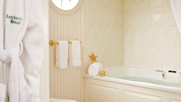 A bathroom with a bathtub, toilet, and a window.