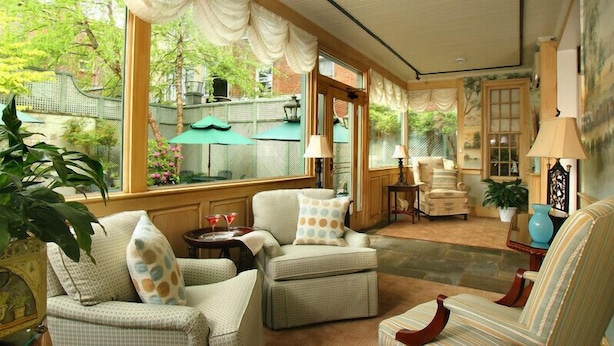 Una habitación acogedora con muebles de mimbre, un comedor con mesa y sillas, y ventanas grandes con cortinas.