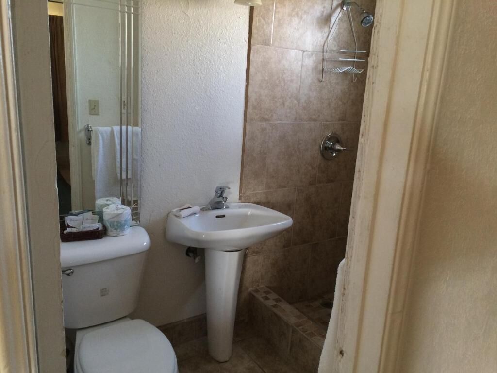 Un baño pequeño con inodoro, lavamanos y zona de ducha.