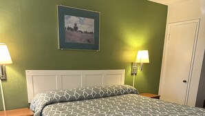 A bedroom with a bed, nightstands, a framed picture on the wall, and a door. - Budget Inn and Suites El Centro (El Centro)